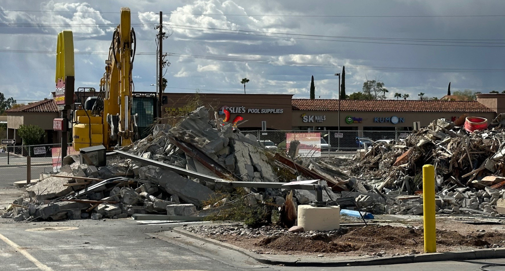 A photograph of the scene of a McDonald's restaurant under demolition. Only the  Golden Arches sign remains.